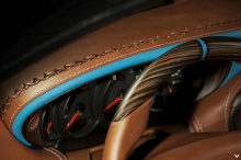 Обновленный автомобиль имеет совершенно новую отделку тонкой коричневой кожей с бело-синей контрастной строчкой. Что бросается в глаза, так это верхняя часть интерьера: X-образный элемент с кожаными вставками. Лицевая сторона панели покрыта синим цве
