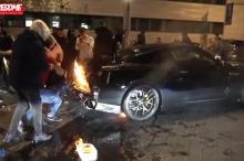 Некоторые используют куртки, чтобы тушить пламя, а другие обрызгивают машину стеклоочистителем. Несмотря на их усилия, огонь под GT-R продолжает разгораться.